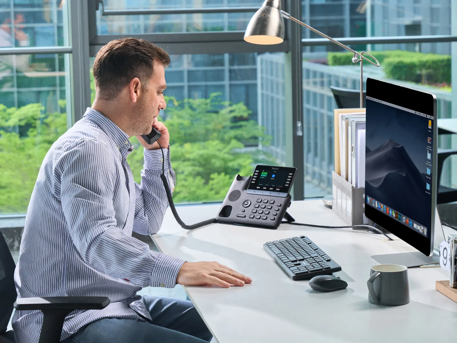 Muž telefonuje cez Yealink SIP-T74W v kancelárii