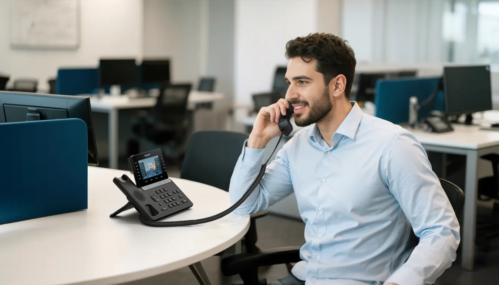 Manažér telefonuje cez Yealink SIP-T85W pri pracovnom stole